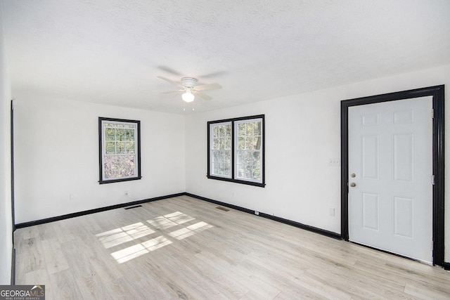 unfurnished room featuring a healthy amount of sunlight, a textured ceiling, and light hardwood / wood-style flooring