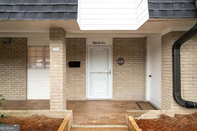 entrance to property with brick siding and a porch