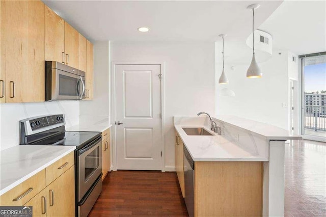 kitchen featuring sink, kitchen peninsula, pendant lighting, stainless steel appliances, and light stone countertops