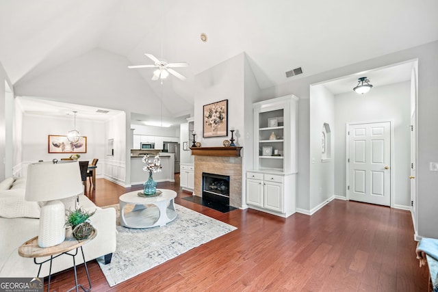 living room with ceiling fan, a fireplace, dark hardwood / wood-style floors, and high vaulted ceiling