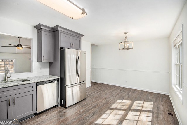 kitchen featuring visible vents, light stone counters, gray cabinets, stainless steel appliances, and a sink