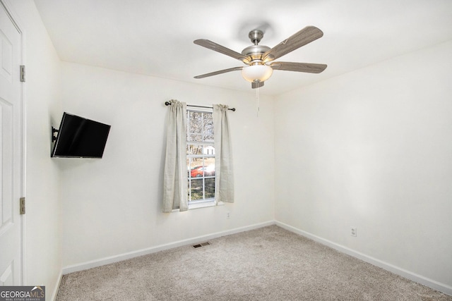 spare room featuring light colored carpet, ceiling fan, visible vents, and baseboards