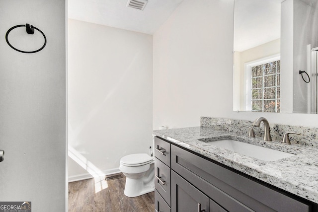 bathroom featuring toilet, vanity, wood finished floors, and visible vents