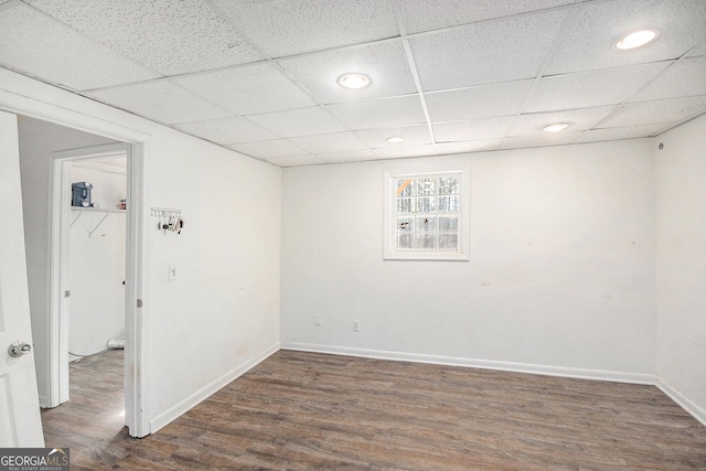 basement with a paneled ceiling, baseboards, and dark wood-type flooring