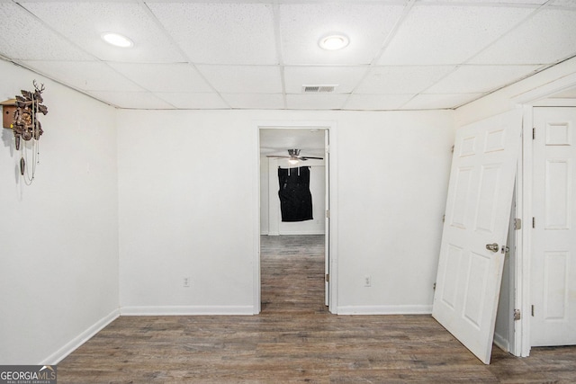 empty room featuring dark wood-style floors, a paneled ceiling, visible vents, and baseboards