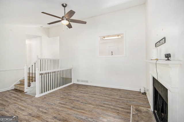 unfurnished living room with a fireplace, visible vents, ceiling fan, wood finished floors, and baseboards