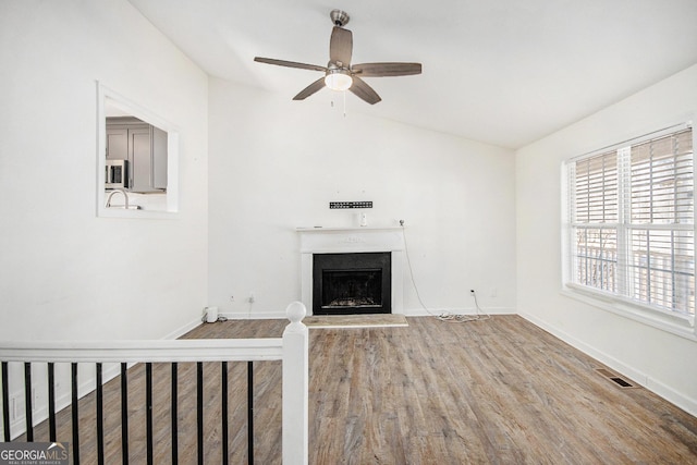 unfurnished living room featuring baseboards, visible vents, a fireplace with raised hearth, and wood finished floors