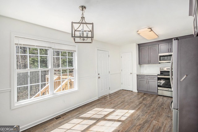 kitchen with dark wood-style floors, decorative light fixtures, stainless steel appliances, light countertops, and visible vents