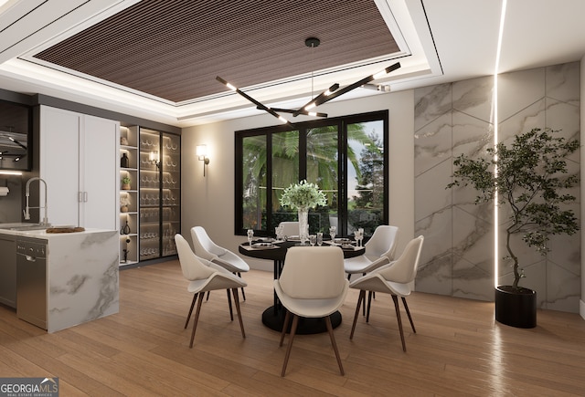 dining area featuring sink, light hardwood / wood-style floors, and a raised ceiling