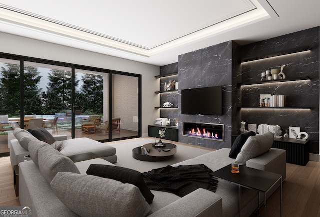 living room with hardwood / wood-style floors, a high end fireplace, and a tray ceiling