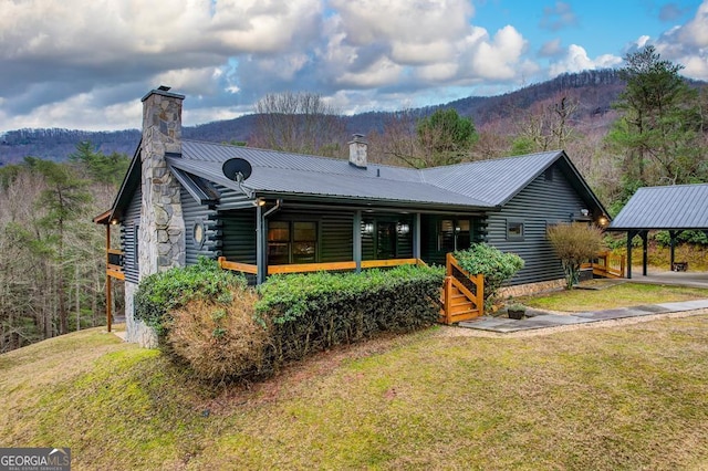 back of property featuring a carport, a yard, and a mountain view