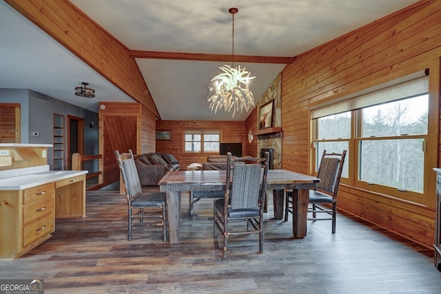 dining space featuring dark hardwood / wood-style flooring, wooden walls, lofted ceiling with beams, and a chandelier