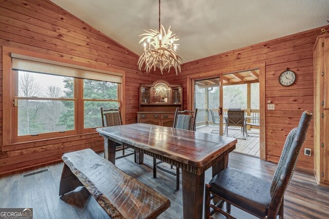 dining area with a notable chandelier, lofted ceiling, dark hardwood / wood-style floors, and a wealth of natural light