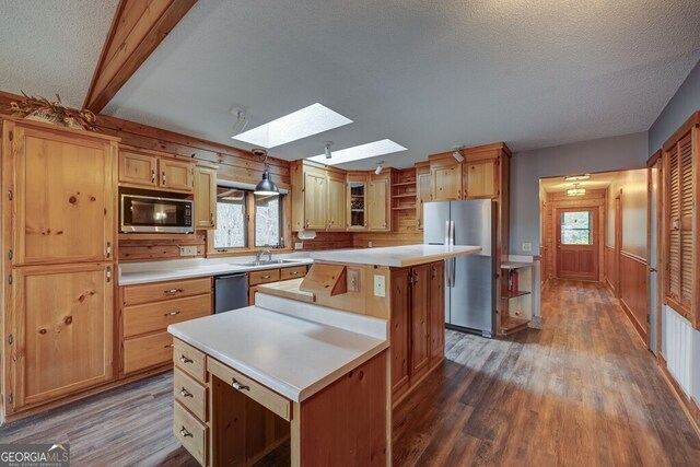 kitchen featuring a skylight, a center island, hanging light fixtures, appliances with stainless steel finishes, and dark hardwood / wood-style floors