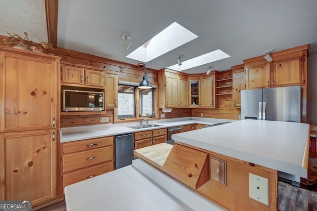 kitchen featuring appliances with stainless steel finishes, a center island, sink, and hanging light fixtures