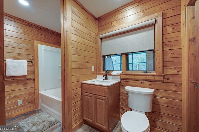 bathroom with a tub to relax in, toilet, wood walls, wood-type flooring, and vanity