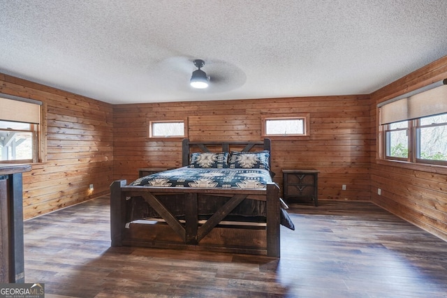 bedroom featuring dark wood-type flooring, wooden walls, and a textured ceiling