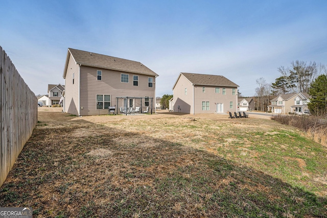 back of house featuring fence, a residential view, a patio area, and a lawn