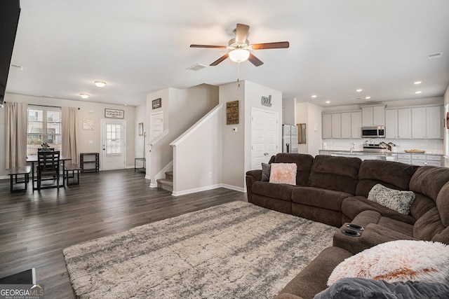 living area featuring recessed lighting, dark wood-style floors, visible vents, baseboards, and stairs