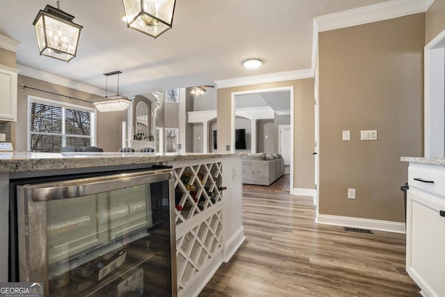 kitchen with wine cooler, pendant lighting, crown molding, white cabinets, and wood finished floors