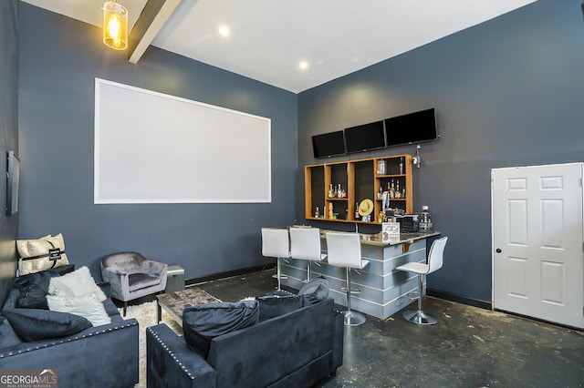 cinema room with a dry bar, concrete floors, and baseboards