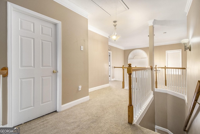 hallway featuring light colored carpet, an upstairs landing, baseboards, ornamental molding, and attic access