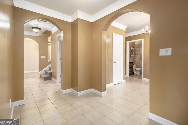 corridor featuring light tile patterned floors, baseboards, and crown molding