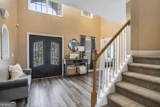 entryway featuring visible vents, wood finished floors, a high ceiling, stairs, and french doors