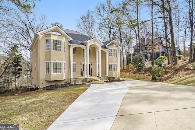 greek revival house featuring a front lawn and stucco siding