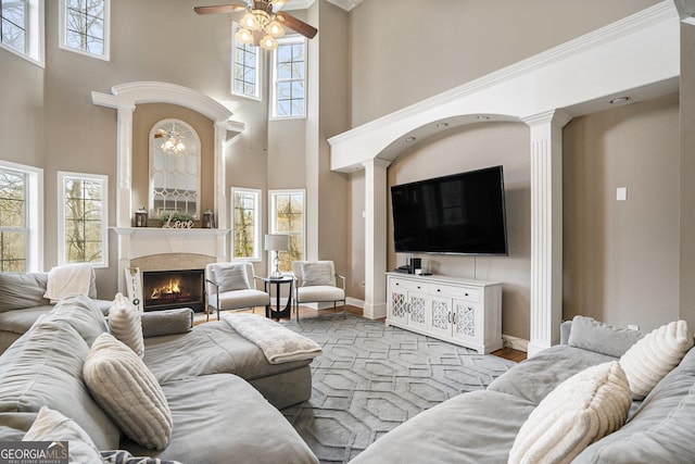 living room featuring baseboards, ceiling fan, a premium fireplace, light wood-style flooring, and ornamental molding