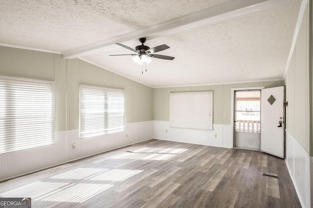 empty room featuring lofted ceiling with beams, ceiling fan, light hardwood / wood-style floors, crown molding, and a textured ceiling