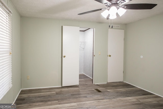 unfurnished bedroom featuring ceiling fan, wood-type flooring, and a textured ceiling