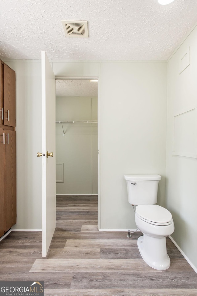 bathroom with wood-type flooring and a textured ceiling