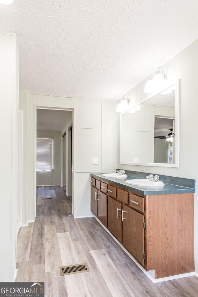 bathroom featuring vanity, hardwood / wood-style floors, ceiling fan, and a textured ceiling