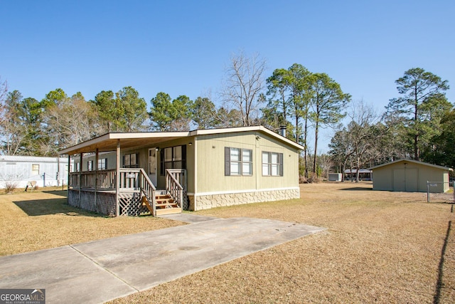 manufactured / mobile home with a porch, a front lawn, and a storage shed