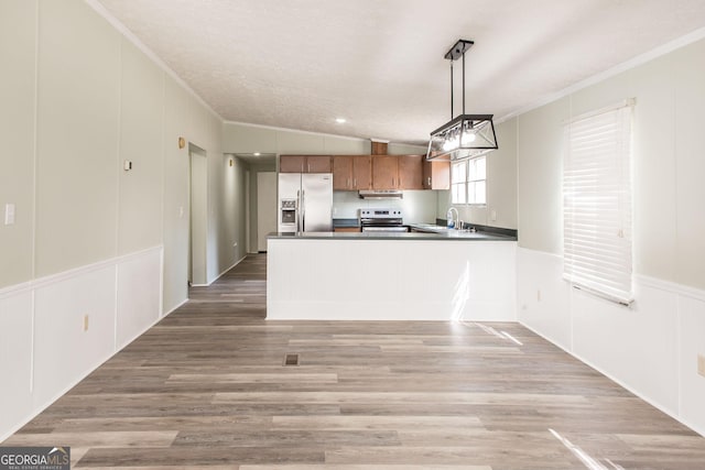 kitchen featuring hardwood / wood-style flooring, appliances with stainless steel finishes, hanging light fixtures, ornamental molding, and kitchen peninsula