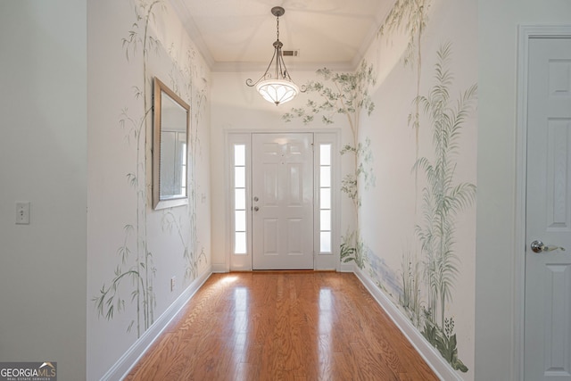 entrance foyer featuring ornamental molding and hardwood / wood-style floors