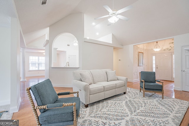 living room with light hardwood / wood-style flooring, sink, ceiling fan, high vaulted ceiling, and ornate columns