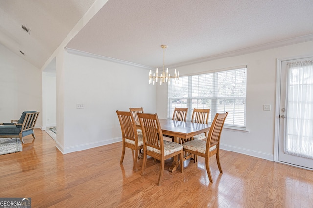 dining area featuring a notable chandelier, light hardwood / wood-style floors, crown molding, and a textured ceiling