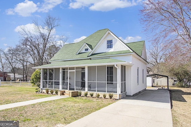 view of front of home featuring a porch, concrete driveway, a sunroom, a carport, and a front lawn