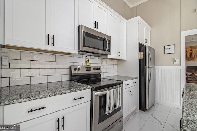 kitchen with marble finish floor, stainless steel appliances, light stone counters, and white cabinetry