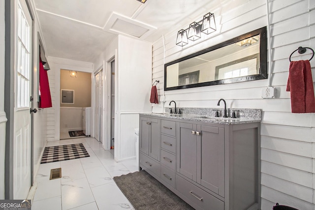 full bathroom with double vanity, marble finish floor, a sink, and a wainscoted wall