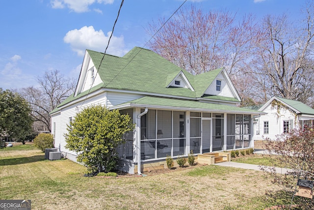 view of front of house with central AC, a front yard, and a sunroom