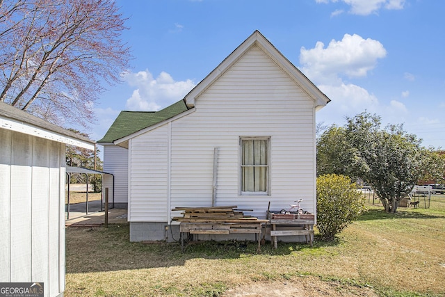 rear view of property with a detached carport and a yard