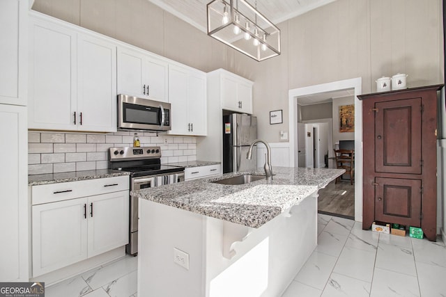 kitchen featuring marble finish floor, stainless steel appliances, an island with sink, and decorative light fixtures