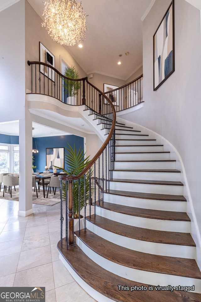 staircase with a notable chandelier, ornamental molding, tile patterned floors, and a high ceiling