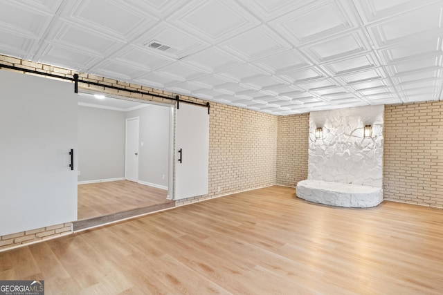 finished below grade area featuring an ornate ceiling, wood finished floors, brick wall, and a barn door