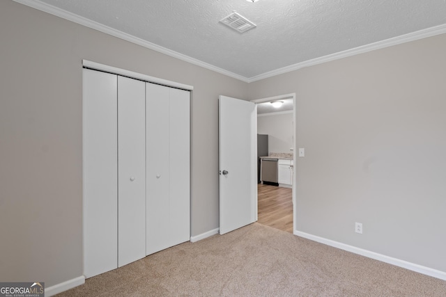 unfurnished bedroom featuring light colored carpet, ornamental molding, a closet, and a textured ceiling