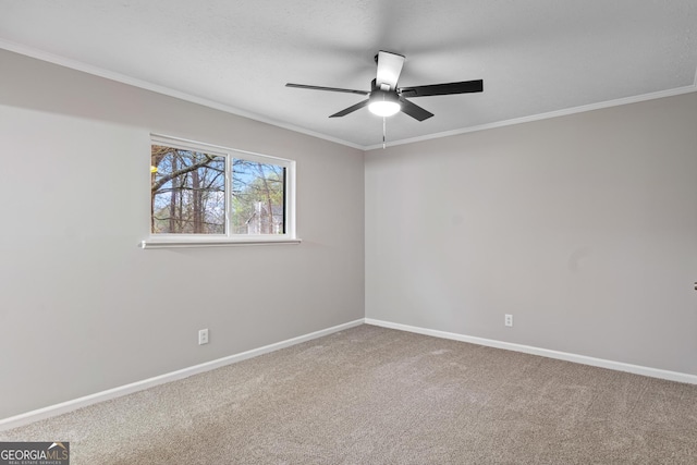 carpeted spare room with a ceiling fan, crown molding, and baseboards
