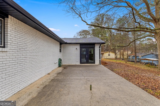 doorway to property with french doors, brick siding, a patio area, and fence
